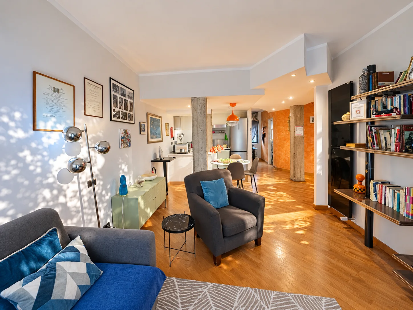 Loft-style living room with armchair, bookcase and view of the dining area